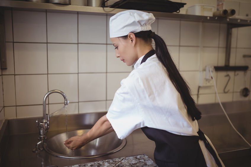 Female chef washing hands in the commercial kitchen